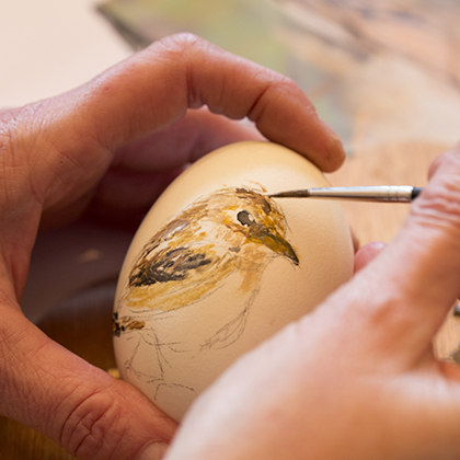 Schildersbenodigdheden en een ei met een vogel erop geschilderd.